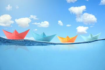 Paper boats on sea water surface and underwater view. Sky with clouds above
