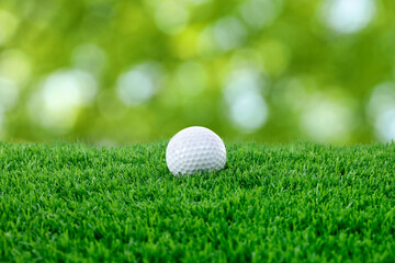 Golf ball on green grass against blurred background