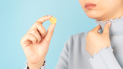 Woman taking medical lozenges with honey lemon flavored for relief sore throat, irritating cough and mouth pain. Close up of female feeling sick and cold over light blue backgroud. Health care.