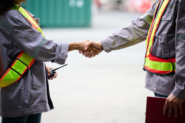 Fototapeta premium Engineers or workers shaking hands before starting to work at containers yard