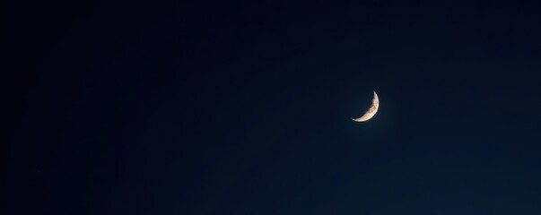 Slender silver crescent moon hangs in inky black sky , space, midnight, isolated moon