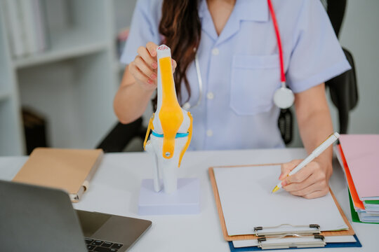 Orthopedic surgeon shows knee model to patient in human knee hospital. Knee joint diseases and disorders, knee pain, orthopedic surgery, chiropractic, office syndrome, medical concept.