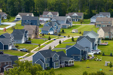 Aerial view of private residential houses in rural suburban sprawl area in Rochester, New York. Upscale suburban homes with large backyards and green grassy lawns in summer season