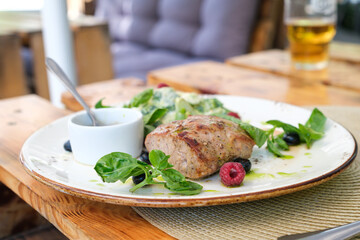 Dish with grilled veal fillet and basil in a cozy open-air restaurant. Healthy eating, outdoor restaurant, and seasonal food. Real life.