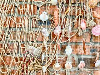 Decorative display of seashells and fishing net against a rustic brick wall with ample space for text