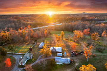 Large traditional homes in forest of autumn colors in Appalachian USA. Yellow and orange trees at sunset in North Carolina countryside.
