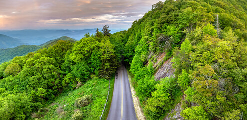 Winding parkway road in mountain forest with green canopies in summertime. Driving in North...