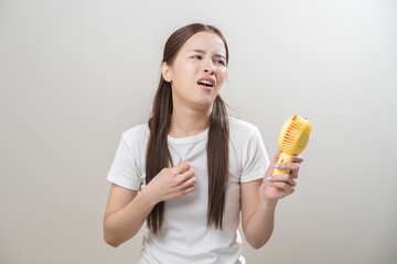 Suffering summer heat wave stroke, hot weather, tired asian young woman sweaty and thirsty, refreshing with hand in blowing, wave fan to ventilation when temperature high, isolated on background.