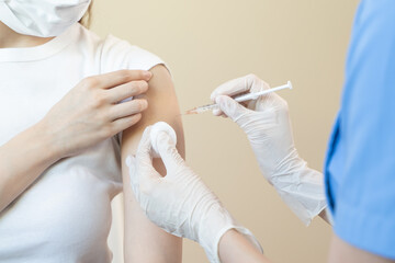 People getting a vaccination to prevent pandemic concept. Woman in medical face mask  receiving a dose of immunization coronavirus vaccine from a nurse at the medical center hospital
