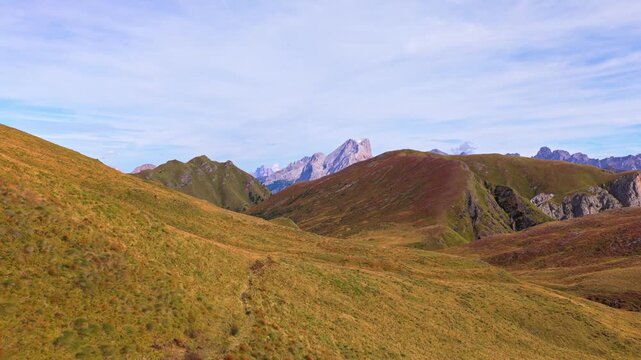 Veduta aerea mozzafiato delle Dolomiti con valli verdi, sentieri alpini e imponenti montagne rocciose sotto un cielo limpido. Un paesaggio naturale spettacolare che rappresenta la bellezza delle Alpi
