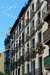 Obraz premium Colorful building facades line a sunny street, adorned with decorative flags