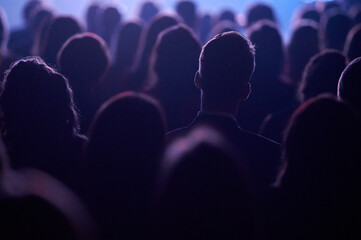 Head silhouette framing bright screen at Gdynia tech talk, blue violet rim light, landscape...
