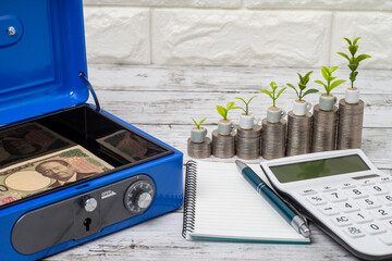 手提げ金庫に入った一万円札と積みあがったコインと電卓