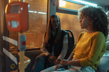 Two young women conversing on a bus at night