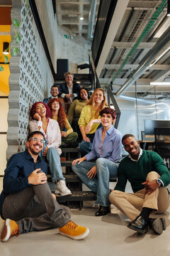 Diverse business team smiling and relaxing on office stairs