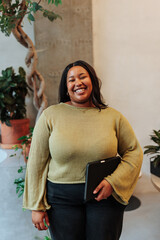 Smiling businesswoman holding tablet in modern office with plants