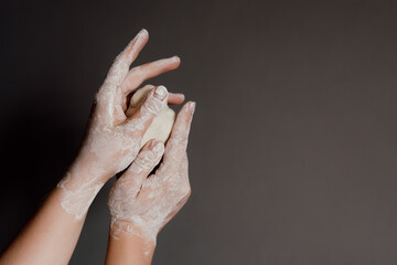 Close up of female hands stained with clay holding a piece of white clay on gray background, horizontal image with copy space for text, concept of pottery, creative hobby and mindfulness.
