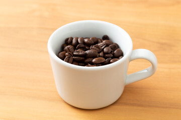 カップに入ったコーヒー豆　木目背景