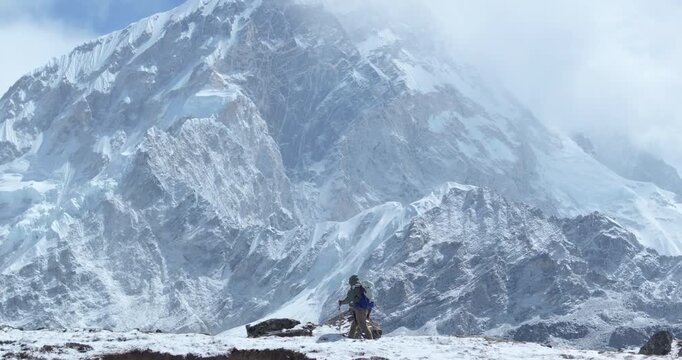 Drone shot of a tourist hiking the Everest Base Camp trek route in Khumbu, Nepal. Morning light reveals snow-capped 8000m Himalayan peaks, breathtaking high-altitude scenery, and a lifetime adventure
