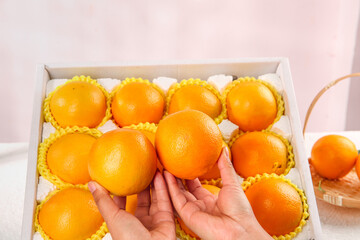 Premium Navel Oranges in Gift Box with Hands Selecting Fresh Citrus Fruit