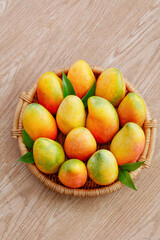 Fresh Ripe Mangoes in Wicker Basket on Wood Table - Tropical Tree-Ripened Fruit with Golden Toffee Colors