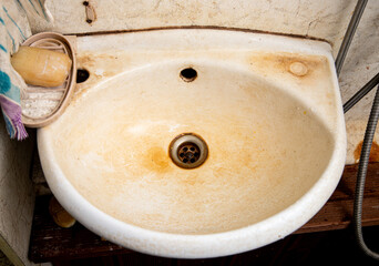 Iron-rich water has damaged the bathroom sink and left an ugly orange layer of residue on it.