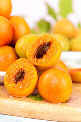 Fresh Xinjiang Apricots Halved on Wooden Board - Small Orange Stone Fruits with Shallow Focus