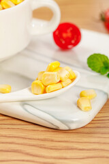 Fresh Golden Sweet Corn Kernels on White Spoon with Vegetables Display