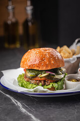 Tasty cheeseburger with fries, sauces and salad on white plate