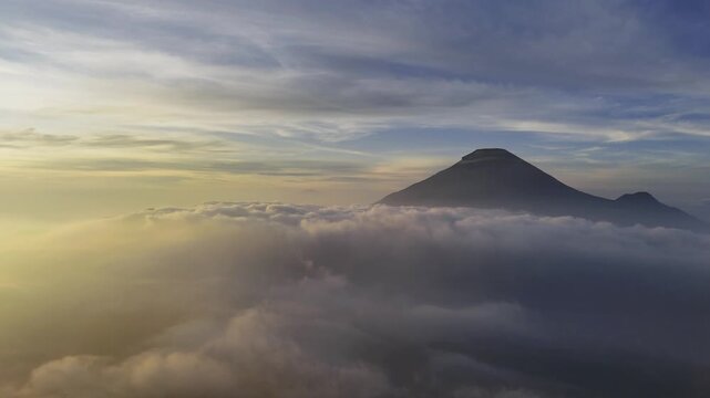 Aerial view of a mountain peak with clouds and golden light