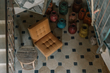 Top view of a rustic interior with a vintage armchair, small wooden round table, and colorful...