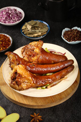 Deep braised pig tails and trotters traditional Chinese cuisine with aromatic spices on wooden serving plate