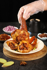 Chef Serving Crispy Roasted Pork Knuckle with Golden Skin in Professional Kitchen Setting