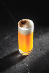 Highball sour cocktail with foam and spices on dark marble table surface