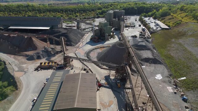 Aerial drone view of huge quarry mining operational facility, extracting rare earth minerals, heavy plant machinery and industrial conveyor belts in Coalville England UK sunny 