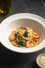 Creamy pasta with shrimp and spinach served in white bowl