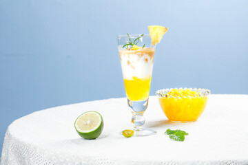 Cold Tropical Pineapple Cocktail with Fresh Lime and Mint Garnish on White Table