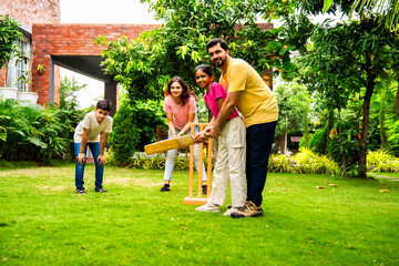Fototapeta premium Indian Asian family bonding through outdoor cricket batting in garden, enjoying fun and play