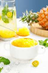 Homemade pineapple jam with fresh tropical fruit and mint on marble background