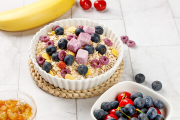 Healthy Oatmeal Breakfast Bowl with Fresh Berries and Fruit Chunks on White Wood Background