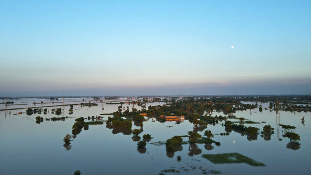 A flooded village and its surrounding agricultural land are seen after dusk, in Pakistan's Punjab province. 