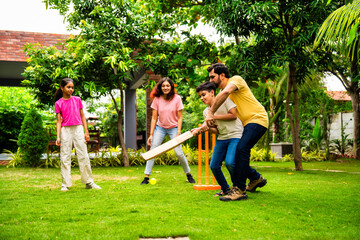 Fototapeta premium Indian family playing cricket batting joyfully in garden during outdoor bonding time