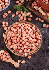 Freshly dug peanut kernels in wicker baskets on dark wet surface display