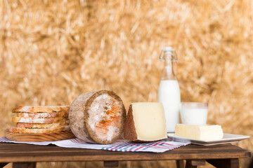 whole head of ripe country cheese and slices and milk in hayloft