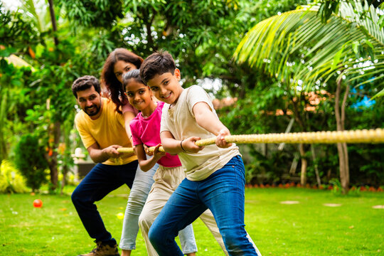 Indian family playing tug of war outdoors, bonding through traditional rope pulling game