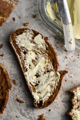 Top view of sliced rye sourdough bread with butter and knife close up. Food background