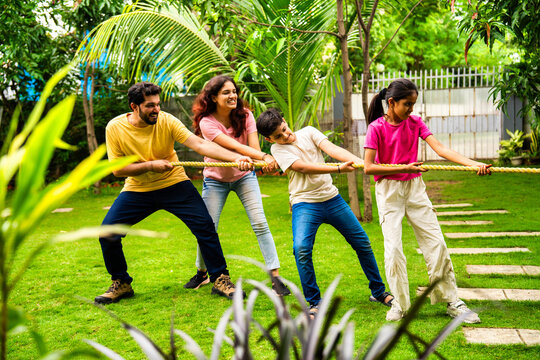 Indian family playing tug of war outdoors, bonding through traditional rope pulling game