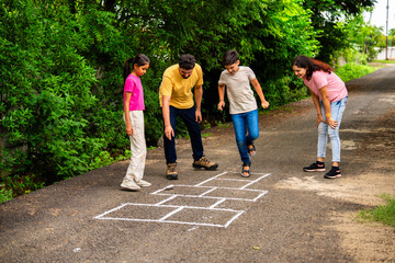 Indian family playing hopscotch or Tikkar Billa outdoors, spending joyful time in garden