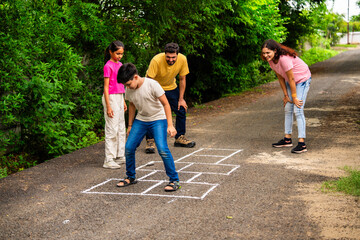 Indian family playing hopscotch or Tikkar Billa outdoors, spending joyful time in garden