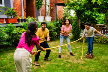 Indian kids enjoy rassi khech game in garden with smiling parents encouraging them